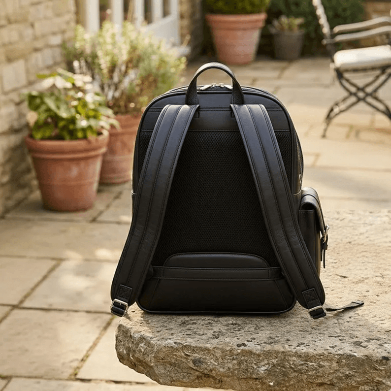 Pet Backpack Carrier | Genuine Leather The back of the Pet Backpack Carrier showing the thick, padded ergonomic shoulder straps and the breathable mesh back panel. The carrier is placed outdoors on a stone ledge surrounded by terracotta planters.