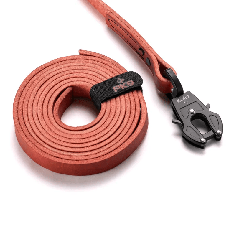 Leather Dog Leash | Aussie Red Hide with Quick-Release Frog Clip product display showing a tightly coiled red leather dog leash next to a detached black tactical swivel frog clip on a white studio background.