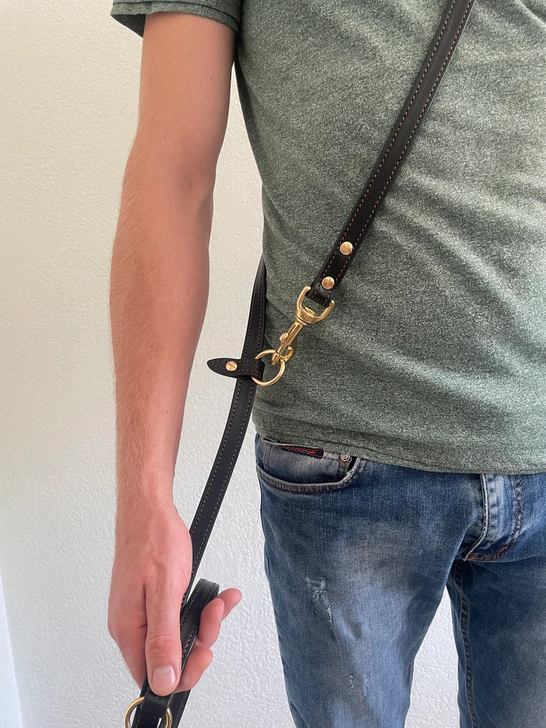 Multi Purpose Dog Leash | Dog Leash Leather 8 ft A side view of a person wearing the leather dog leash across their torso like a crossbody bag. The strap goes from the shoulder to the opposite hip, where it is secured with a brass clip and O-ring, demonstrating hands-free utility.