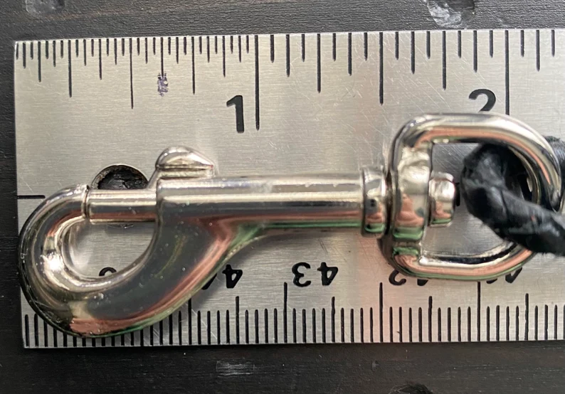 Leather Dog Leash | Braided Kangaroo Leather Dog Show Lead A close-up shot of the silver metal swivel bolt snap clasp laid against a metal ruler. The clasp measures approximately 2 inches in length.