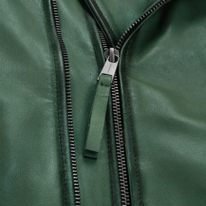 A detailed shot of a metallic zipper on a green leather jacket with a matching leather pull tab.