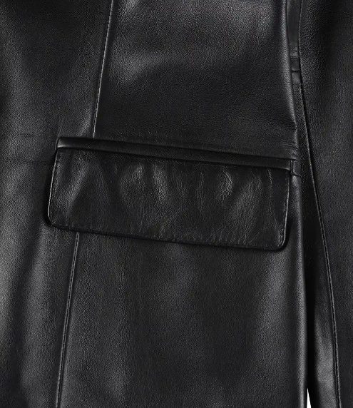 Women's Genuine Leather Jacket | Lambskin Blazer Jacket A close-up, detailed macro shot focusing on one of the rectangular front flap pockets of the black leather jacket. The image emphasizes the fine stitching, the subtle grain texture of the high-quality genuine leather, and the soft sheen of the material.